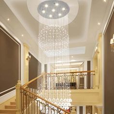 a chandelier hanging from the ceiling in a room with beige walls and stairs