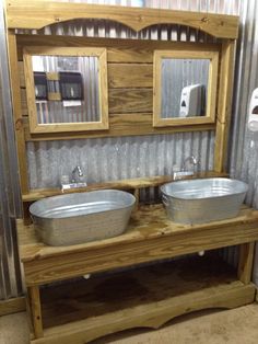 two metal bowls sitting on top of a wooden bench next to a mirror and towel dispenser