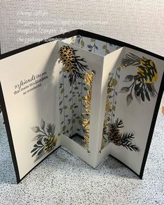 an open card with gold foil flowers and leaves on it, sitting on a table