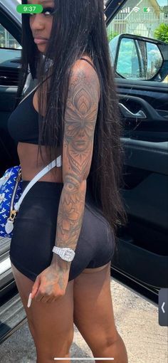 a woman with tattoos standing in front of a car