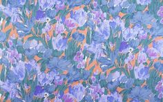 an orange and blue floral print fabric with purple flowers on it's side, as well as green leaves in the background