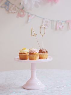 three cupcakes on a cake stand with the number forty