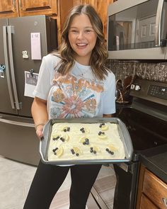 a woman is holding a pan with some food on it and smiling at the camera