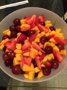 a white bowl filled with fruit on top of a table