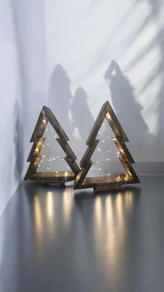 two wooden christmas trees with lights in the shape of trianglees on top of each other