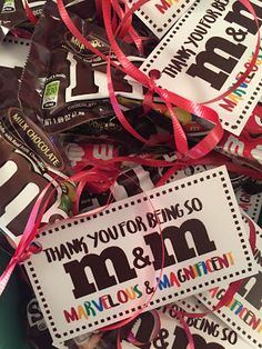 many candy bars are wrapped in red and pink ribbons with the words thank you for being so m & m on them