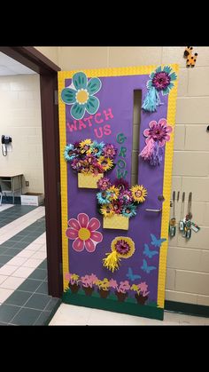 a door decorated with flowers and the words watch us on it in front of a hallway