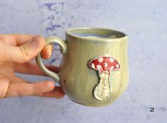 a hand holding a coffee mug with a mushroom on it