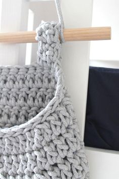 a crocheted bag hanging from a hook on a door handle with a wooden stick in front of it