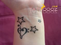 a small wrist tattoo with stars and a heart on the left side of the arm