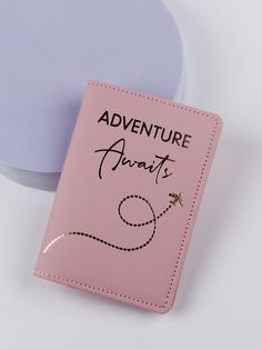 a pink passport case with the words adventure awaits on it next to a blue disc