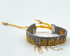 This yellow and grey coloured boho and hippie style bracelet is comfortable to wear and lightweight around the wrist with adjustable sliding knot closure so fits most sizes both women, men and children. It harmonizes with every outfit, every occasion, also perfect as a gift. Lac plated stainless steel chain in silver colour and metallic beads added for modern design. Woven length 13.5cm, extension braided length 9cm, width 1.2cm Designed and made in a smoke free - pet free environment.  All our Handmade Adjustable Cuff Bracelet For Summer, Handmade Trendy Cuff Bracelet For Festivals, Trendy Handmade Cuff Bracelet For Festivals, Adjustable Yellow Friendship Bracelets For Festivals, Trendy Adjustable Yellow Friendship Bracelets, Trendy Yellow Adjustable Friendship Bracelets, Handmade Bohemian Cuff Bracelet For Summer, Adjustable Yellow Beaded Bracelets For Festival, Handmade Trendy Yellow Friendship Bracelets