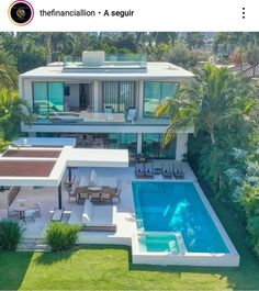 an aerial view of a house with a swimming pool in the foreground and palm trees surrounding it