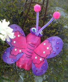 a purple and pink butterfly statue next to a white flower