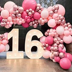 the number sixteen is surrounded by balloons in pink and silver colors on display at an event