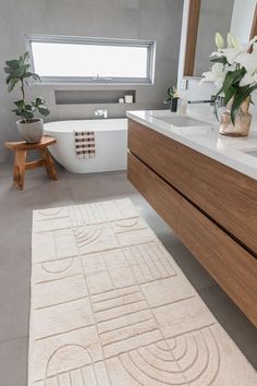 a bathroom with a bathtub, sink, and rug on the floor in front of it