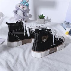 two black sneakers with white laces and a teddy bear