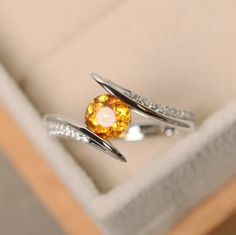 This halo ring features a 6mm round cut citrine and sterling silver finished with rhodium. Customization is available. It is made by hand, and it will take about 7 days to finish the ring after your payment is completed. Main stone: Citrine Citrine weight: Approx 0.95 ct Metal type: sterling silver finished with rhodium Accent stone: cz Customization is available, I also can make it with 14k solid gold (white or yellow or rose) and diamond accent stone, just feel free to contact me. Any question Yellow Gemstone Ring, Bypass Engagement Ring, Citrine Ring Engagement, Special Engagement Ring, Yellow Ring, November Birthstone Ring, Ring Crystal, Yellow Rings, Yellow Gemstones