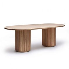 an oval wooden table sitting on top of a white floor