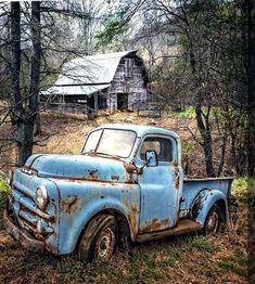 an old blue truck parked in the woods