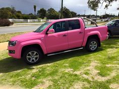 a pink pick up truck parked in the grass