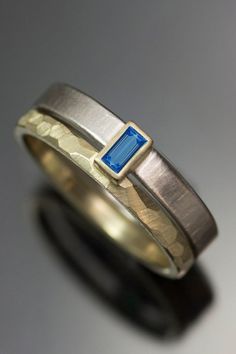 a gold and silver ring with a blue stone in the center on a gray surface