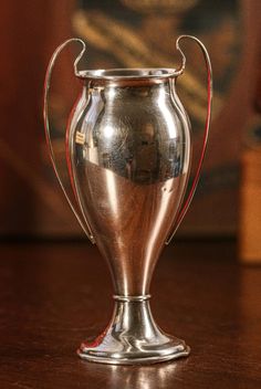 a silver vase sitting on top of a wooden table