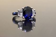 Dekara Designs Collection Metal- 90% Platinum, 10% Iridium. Stones- 1 Natural Untreated 3.88 Carat Oval Cut Ceylon Blue Sapphire. 2 Moon Cut Diamonds, F-G Color VS1 Clarity 0.77 total carats This ring is a size 6, but could be sized up or down a few sizes. This ring could be made in your specific size within 5-10 business days. Could take a little more time due to the ceylon sapphire being a rare stone. The sapphire may be a bit smaller or bigger. We can make the same design in a smaller or bigg Classic Blue Diamond Ring With Brilliant Cut, Classic Blue Brilliant Cut Diamond Ring, Blue Three Stone Round Cut Diamond Ring, Oval Blue Diamond Ring With Accent Stones, Classic Royal Blue Round Ring, Classic Blue Rings With Lab-created Sapphire, Classic Blue Lab-created Sapphire Rings, Classic Blue Sapphire Diamond Ring, Blue Three Stone Sapphire Ring