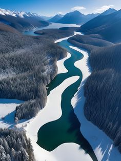 an aerial view of a river surrounded by snow covered mountains and evergreen trees in the distance