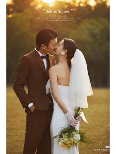 a bride and groom kissing each other in front of the sun with trees behind them