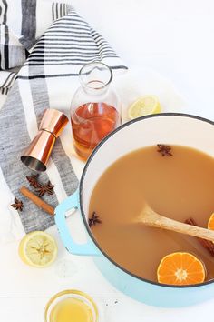 a pot filled with liquid sitting on top of a table next to sliced oranges