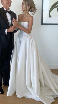 a man in a tuxedo standing next to a woman in a white dress