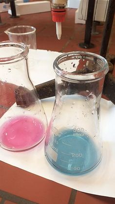 two beakles filled with colored liquids on top of a table