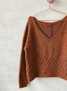 an orange sweater hanging on a white wall next to a heart shaped object with a wooden hanger