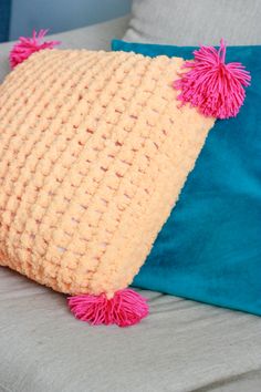 a pillow with pink pom - poms on it sitting on top of a couch