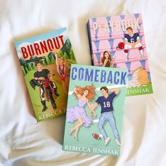 three children's books sitting on top of a white bed next to each other