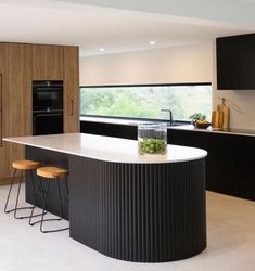 a kitchen with an island and stools next to the counter top in front of a window