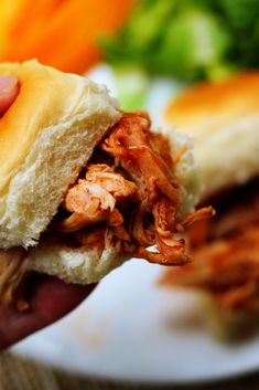 a hand holding a sandwich with meat and cheese