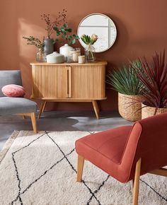 a living room with two chairs and a rug on the floor, one chair has a round mirror above it