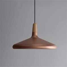 a copper colored light hanging from a black cord on a gray wall with a white background