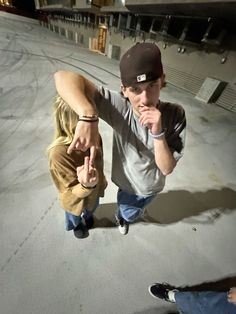 two young men standing next to each other on top of a parking lot at night