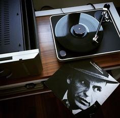 an old record player sitting on top of a wooden table next to a vinyl album