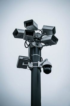 several cameras mounted on top of a black pole