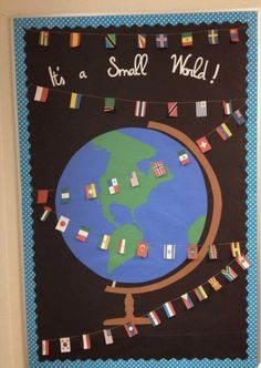 a bulletin board with flags on it and the words its a small world written in black