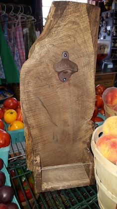 there is a wooden carving on the shelf next to baskets of peaches and other fruit