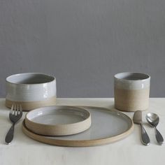 the table is set with dishes and silverware, including two cups and one plate