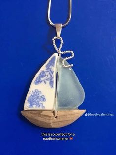 a blue and white sailboat pendant on a chain