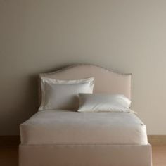 a bed with white sheets and pillows in a room