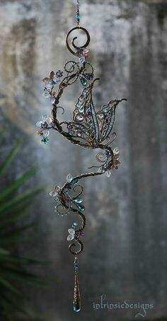 a metal chandelier hanging from a chain with crystal beads and leaves on it