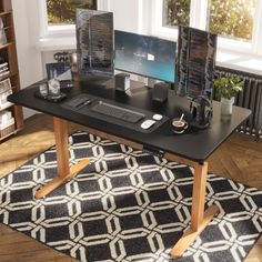 a computer desk with two monitors and a keyboard on it in front of a window